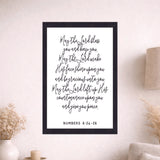 Framed print with a biblical quote on a wall above a sofa in a living room.